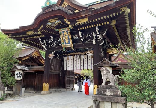The carved and gilded Sanko-mon gate of Kitano Tenmangu with a stone guardian beside it