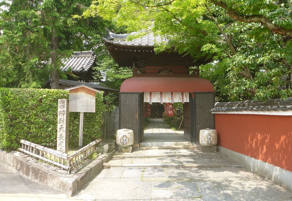 The Ryugu-style gate and red earthen wall of Choken-ji in Fushimi, with its stone name pillar on the left