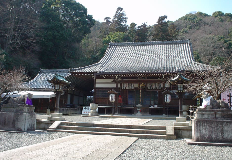 The main hall of Horin-ji on the slope of Arashiyama, with lanterns under its eaves and stone statues by the steps