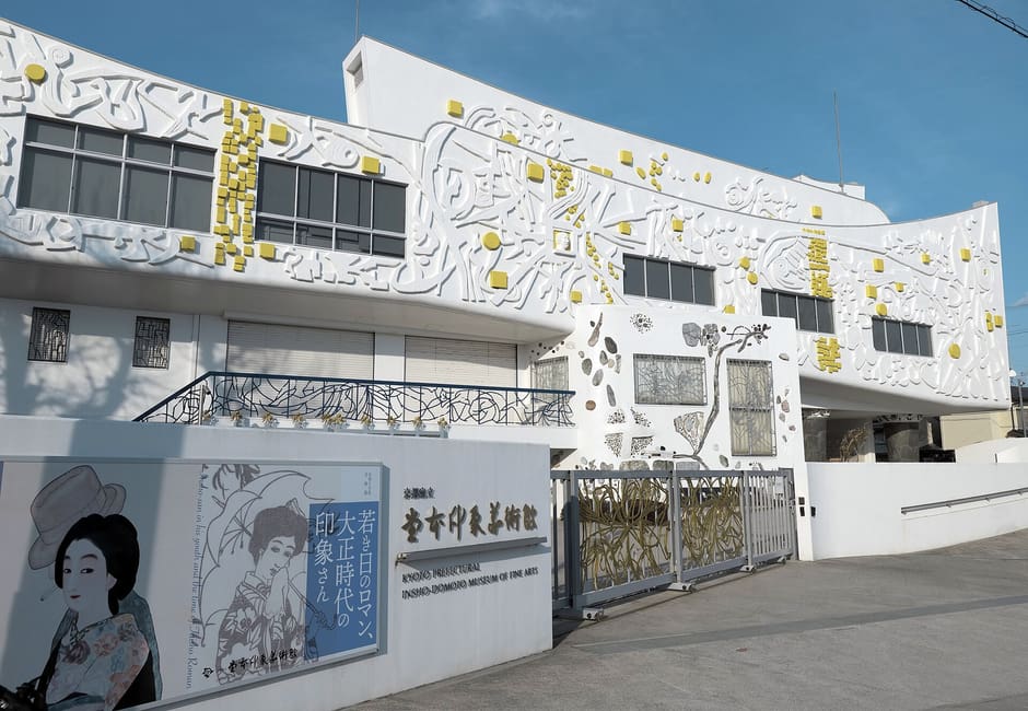 The white facade of the Insho-Domoto Museum of Fine Arts, covered in Domoto Insho's relief patterns, with its name sign