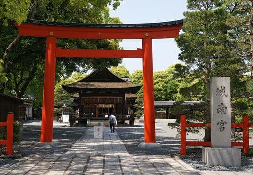 The red torii and stone name pillar of Jonangu, with the shrine gate at the end of the paved approach