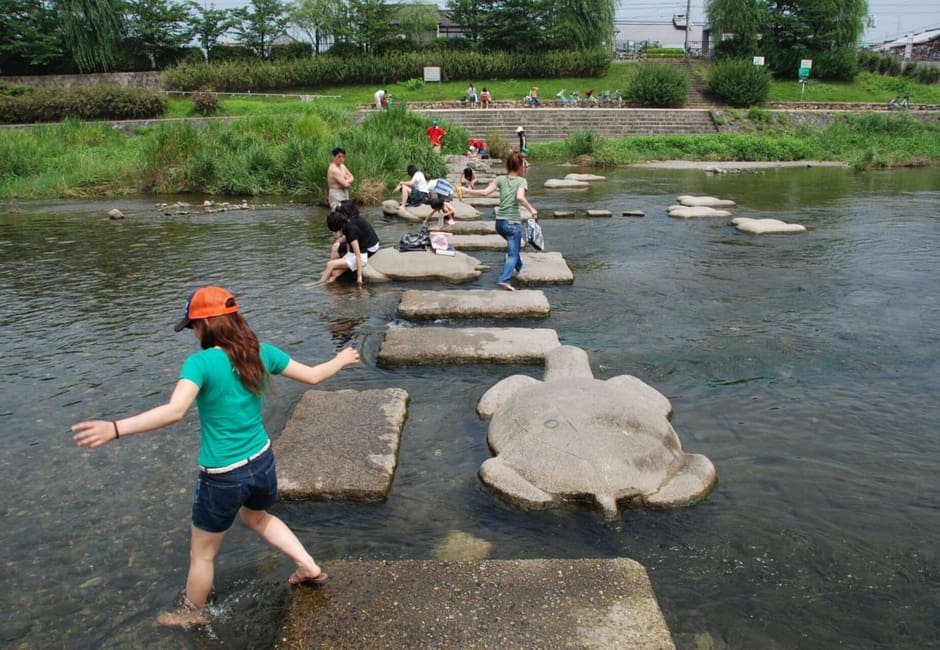 A child hopping across the stepping stones of the Kamogawa Delta