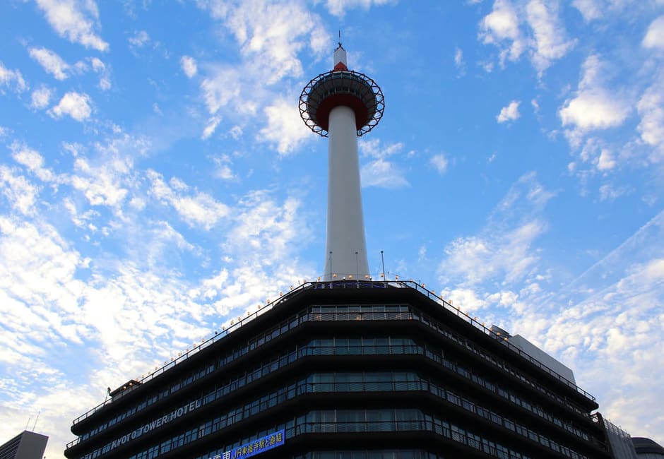 Kyoto Tower rising above its base building against a blue sky