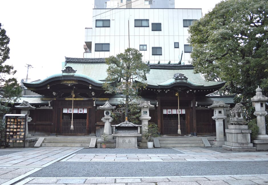 The two main halls of Nagi Shrine standing side by side behind stone lanterns and an offering table