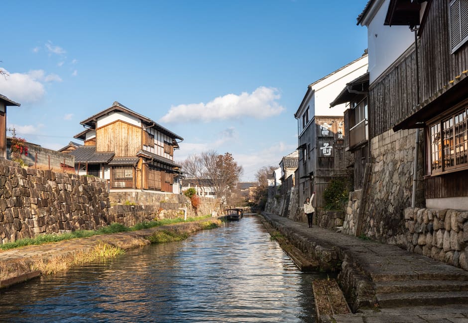 The Hachiman-bori moat in Omihachiman, lined with old storehouses and stone walls under a blue sky