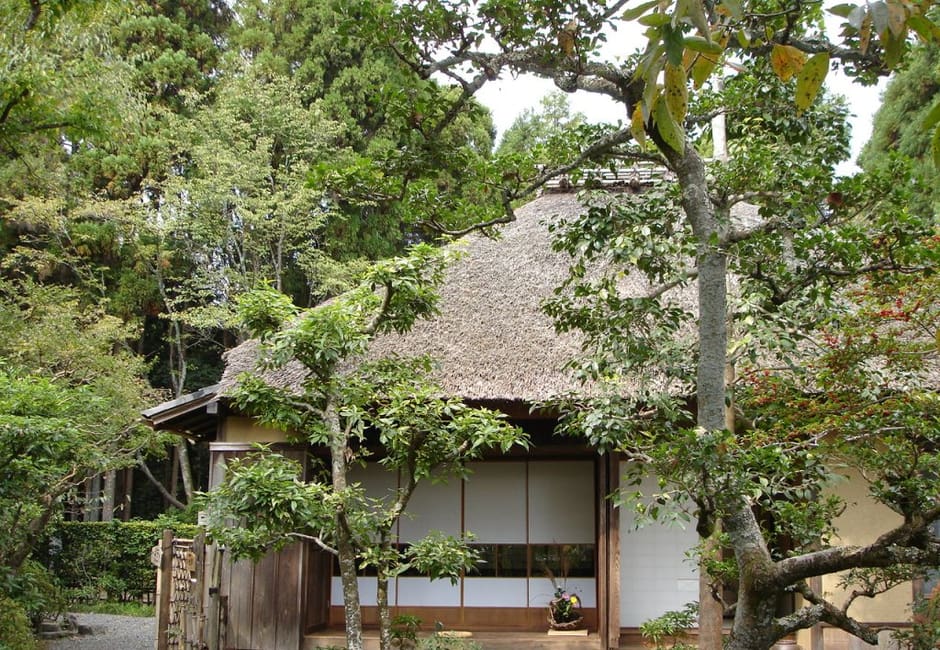 The thatched hut of Rakushisha with its paper screens, seen through the garden trees in Saga