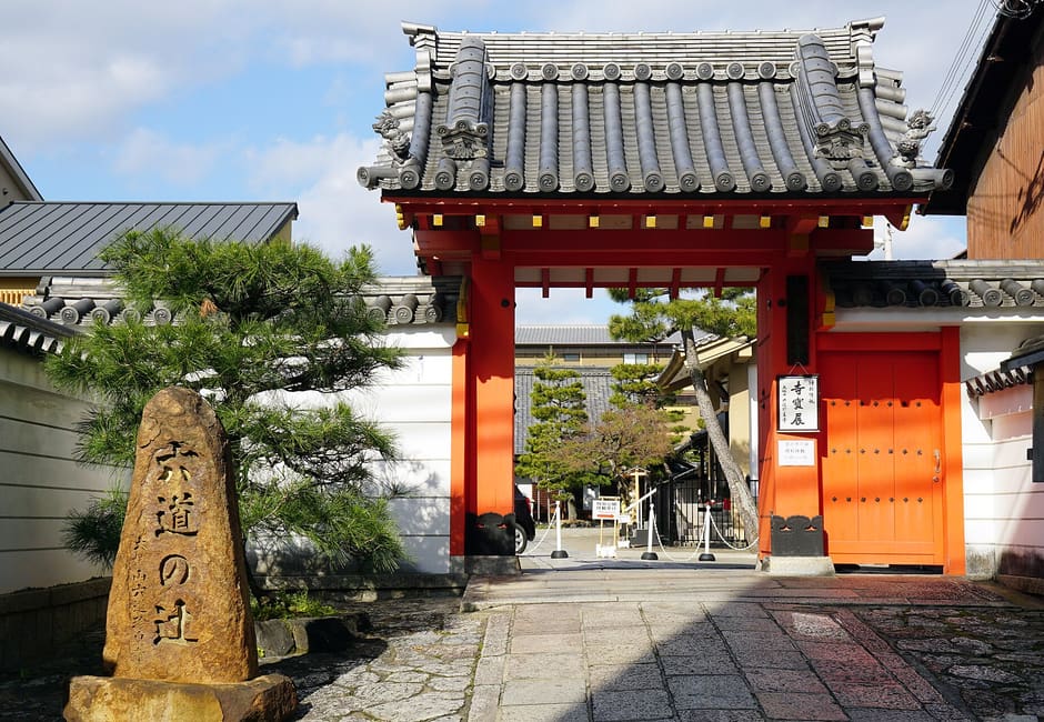The red gate of Rokudo Chinnoji, with the carved Rokudo no Tsuji stone standing in front of it