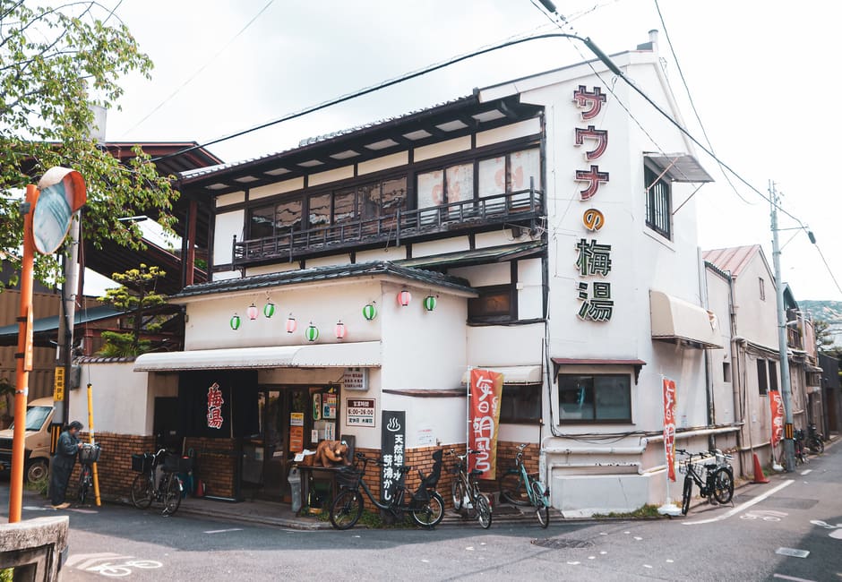 Sauna no Umeyu's white two-storey building with its big vertical sign and bicycles parked out front