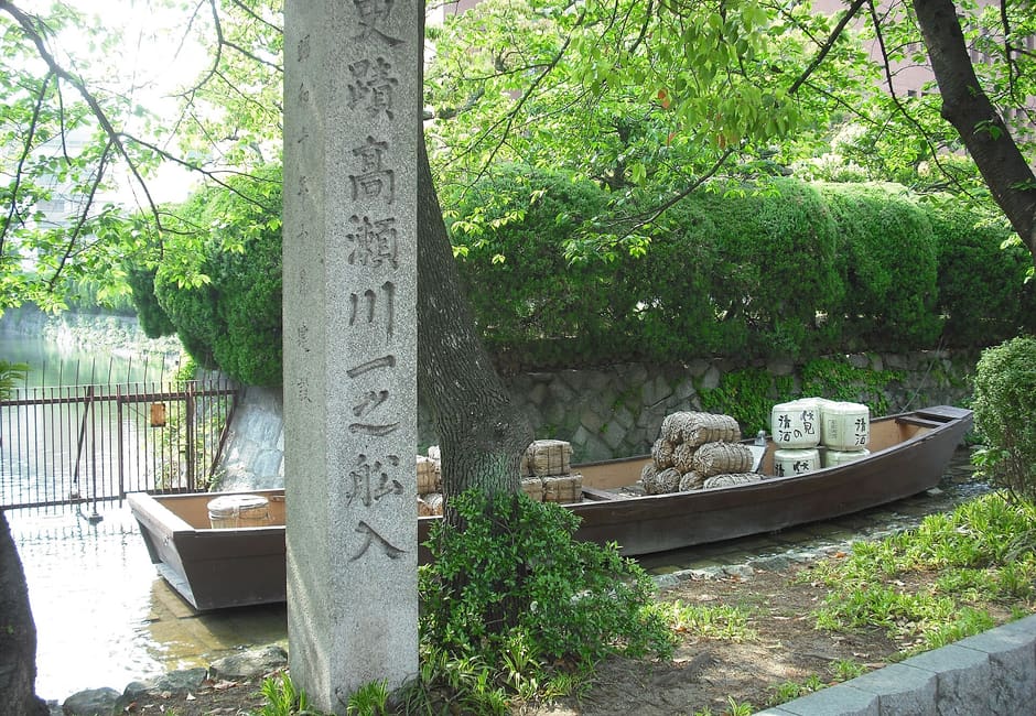 The stone marker of Takase River Ichinofunairi beside a replica takasebune loaded with rice bales and barrels