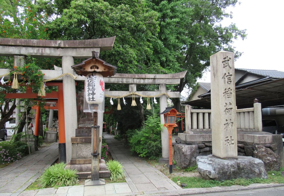 The entrance of Takenobu Inari Shrine, with stone and red torii, a name lantern and the carved stone name pillar