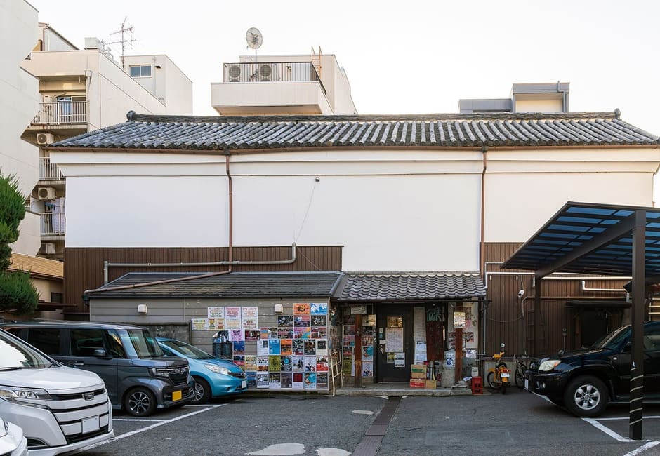 The white plastered sake storehouse of the Taku Taku live venue with posters at its door