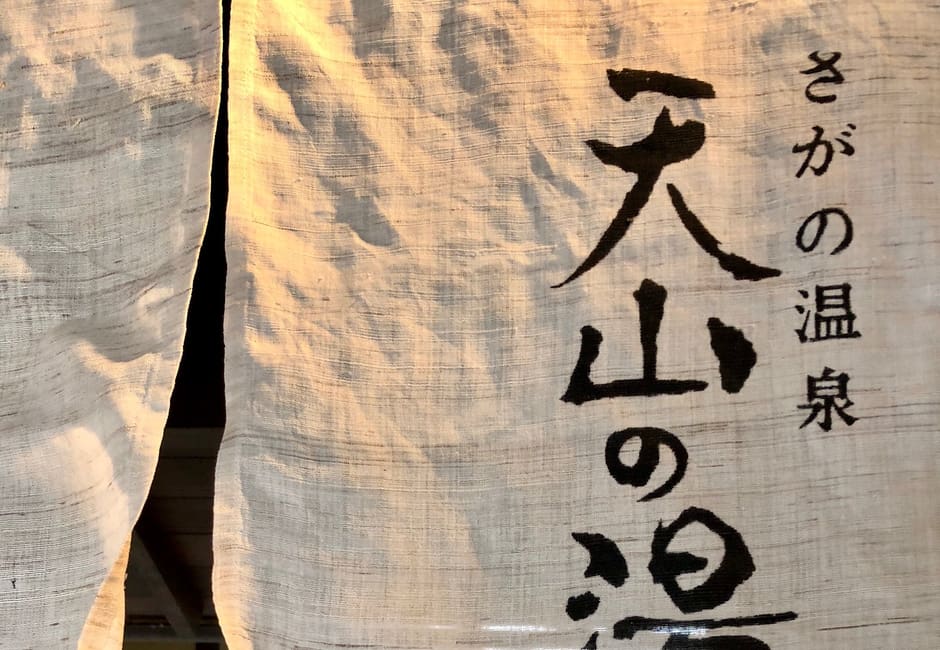 The linen noren at the entrance of Tenzan no Yu, brushed with the name Sagano Onsen Tenzan no Yu