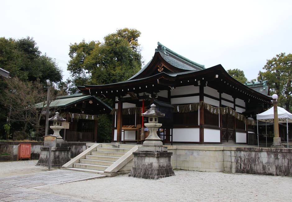The worship hall of Waratenjin Shrine (Shikichi Jinja) in Kyoto, with stone lanterns on the gravel forecourt