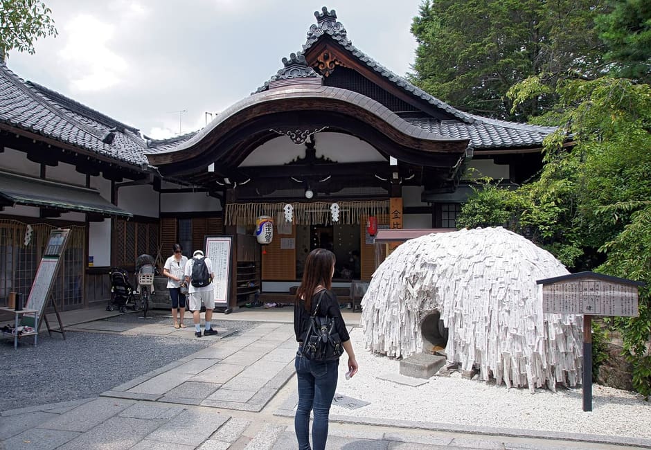 The enkiri stone covered in paper charms in front of the Yasui Konpira-gu hall, Kyoto