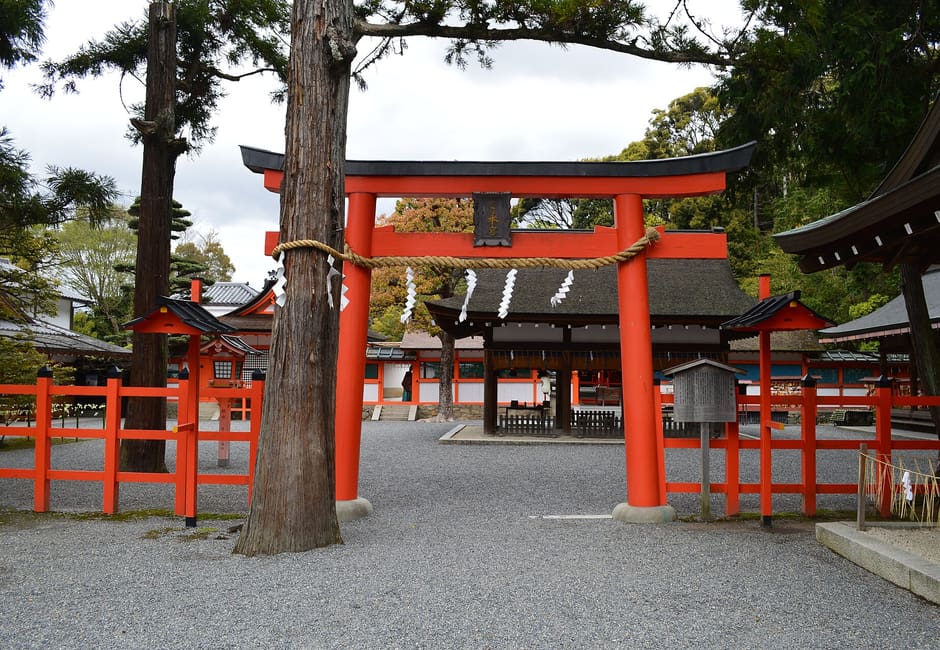 Vermilion torii inside Yoshida Shrine with the red fenced main shrine buildings behind it